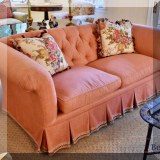 F12. Custom coral-colored sofa with skirt. 30”h x 80”w x 36”d 